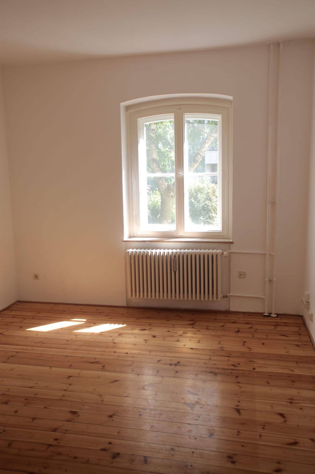 Leerer Altbauraum mit Dielenboden und großem Fenster