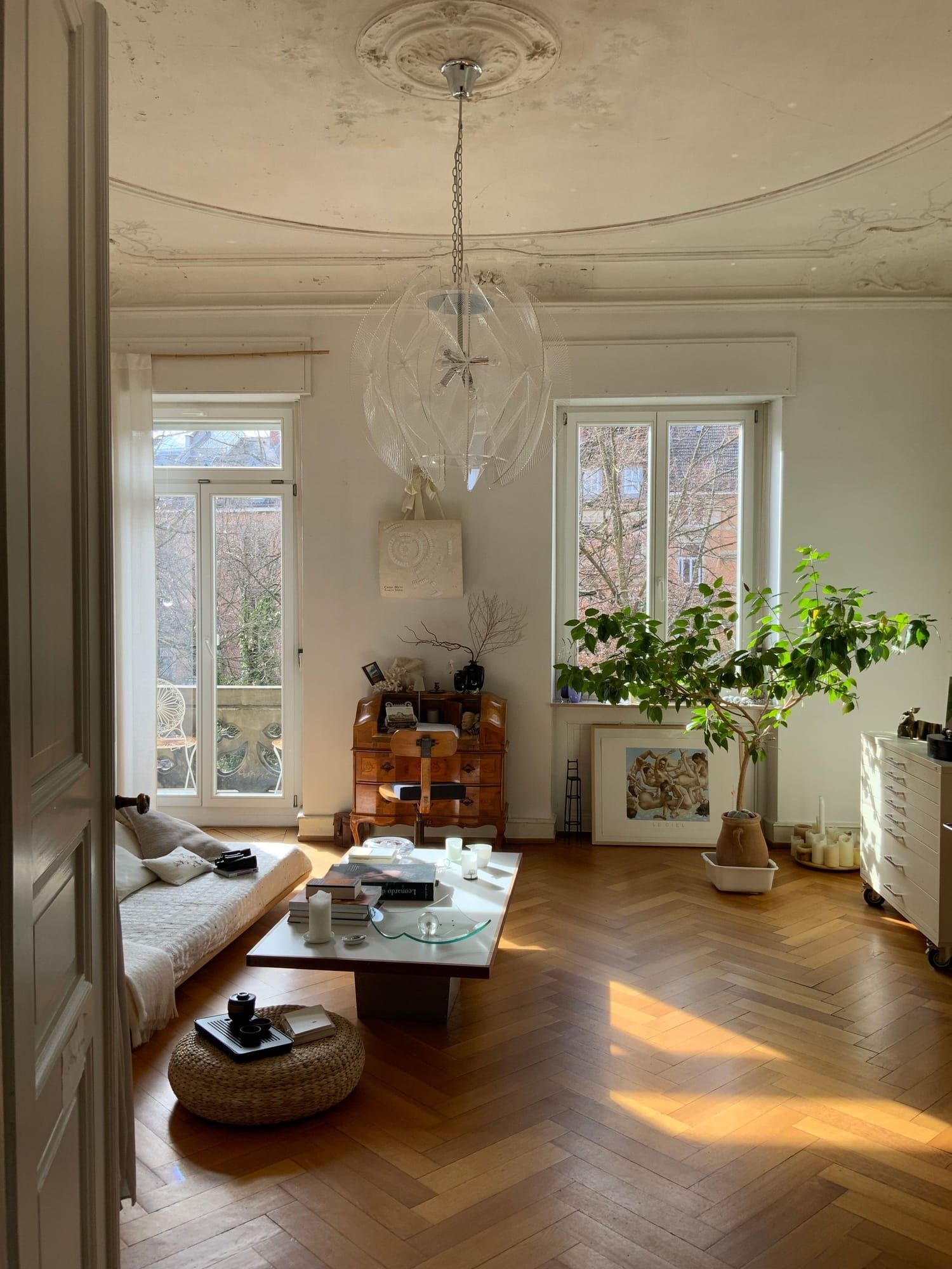 Sonniger Altbauraum mit Parkett, Kronleuchter und Blick zum Balkonfenster