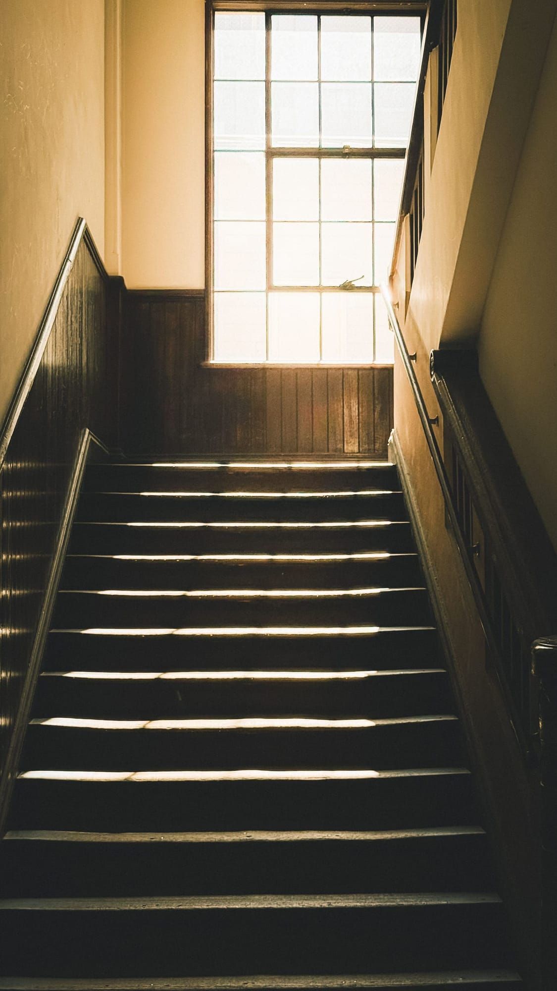 Holztreppe in einem Altbau mit Licht aus hohem Fenster
