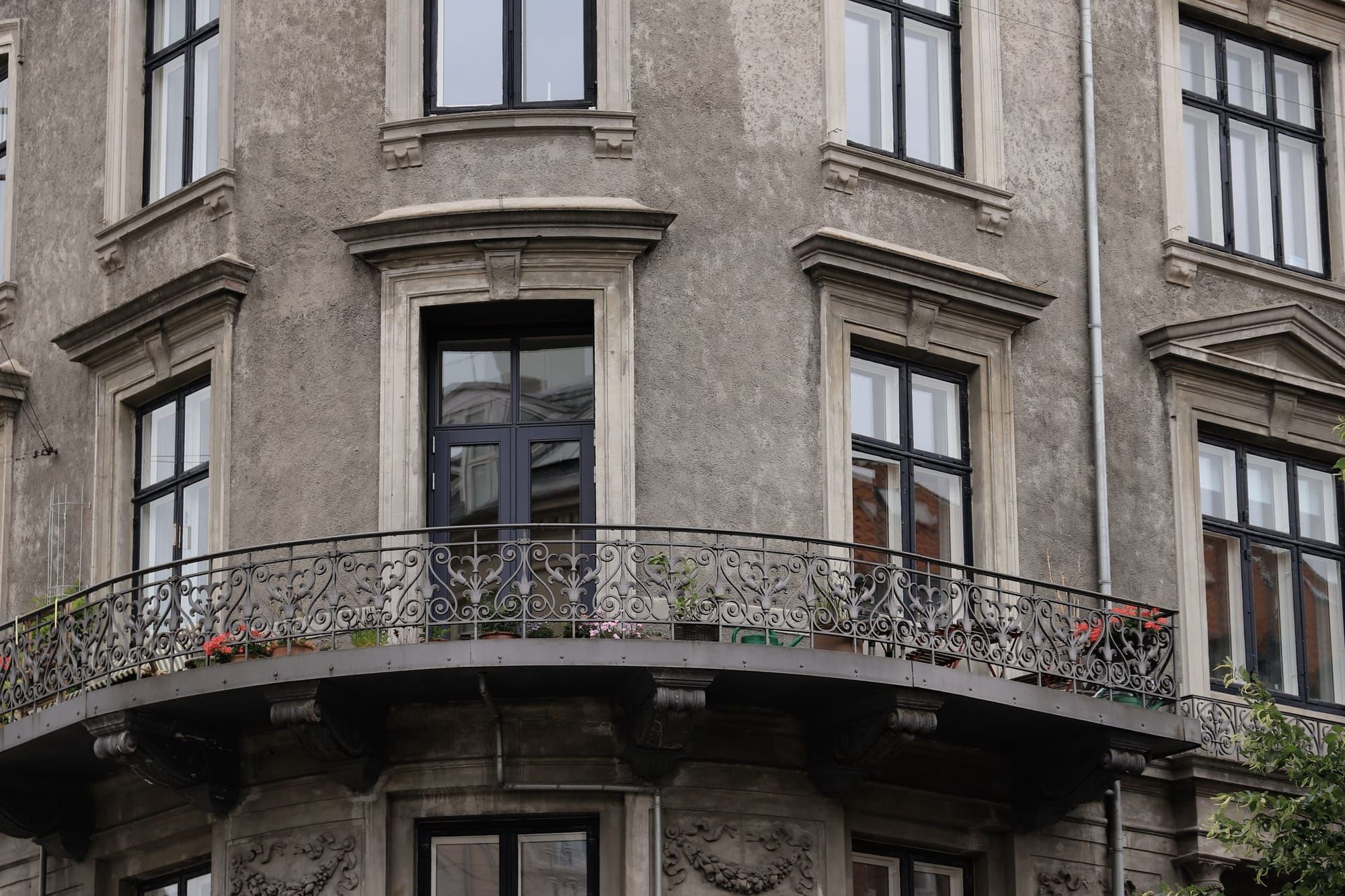 Fassade eines Altbaus mit grauem Putz und schmiedeeisernen Balkonen