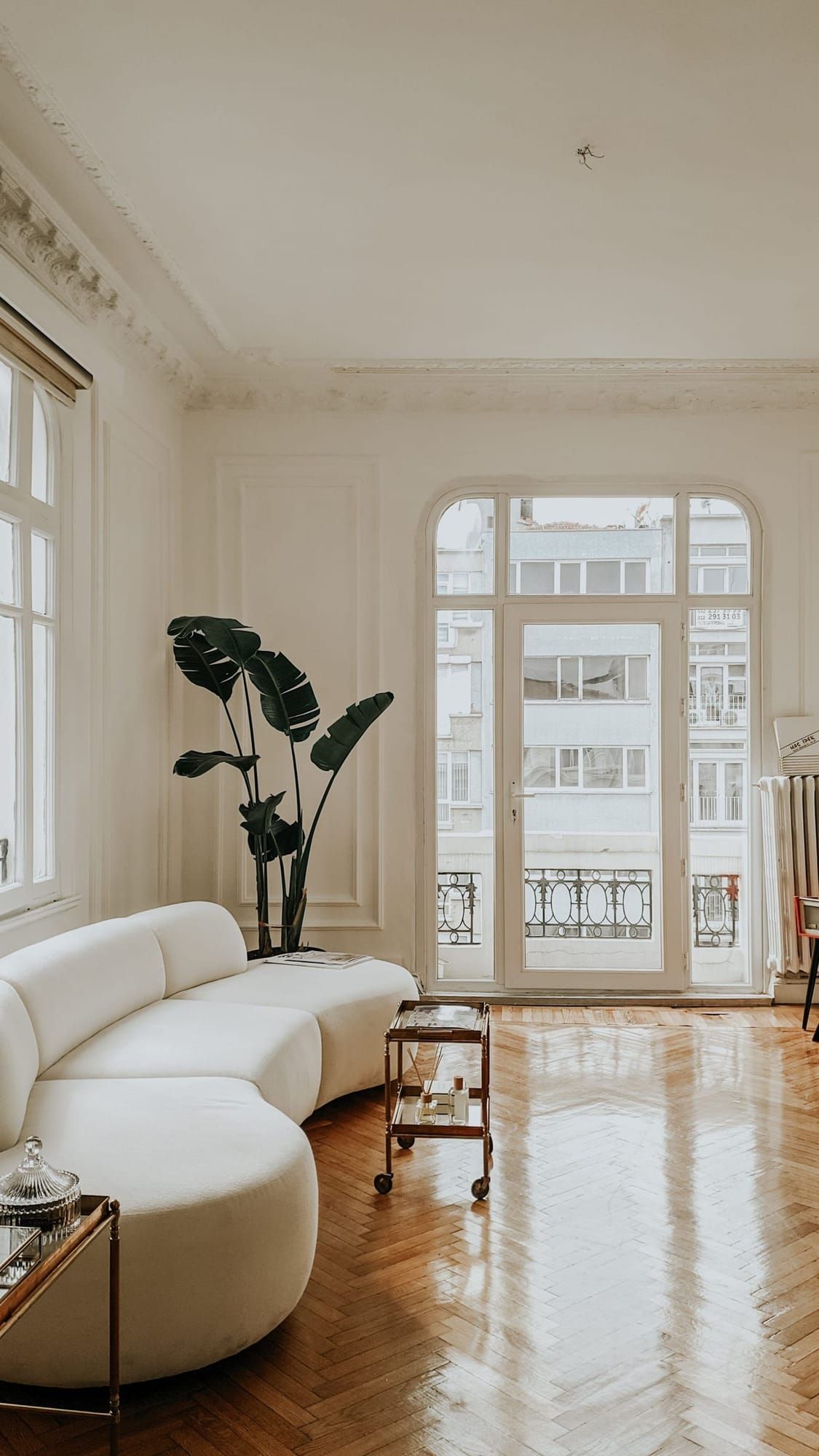 Heller Wohnraum mit hohem Fenster, Pflanze und weißem Sofa